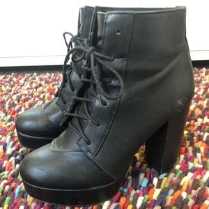 Tall black faux leather lace-up boots.